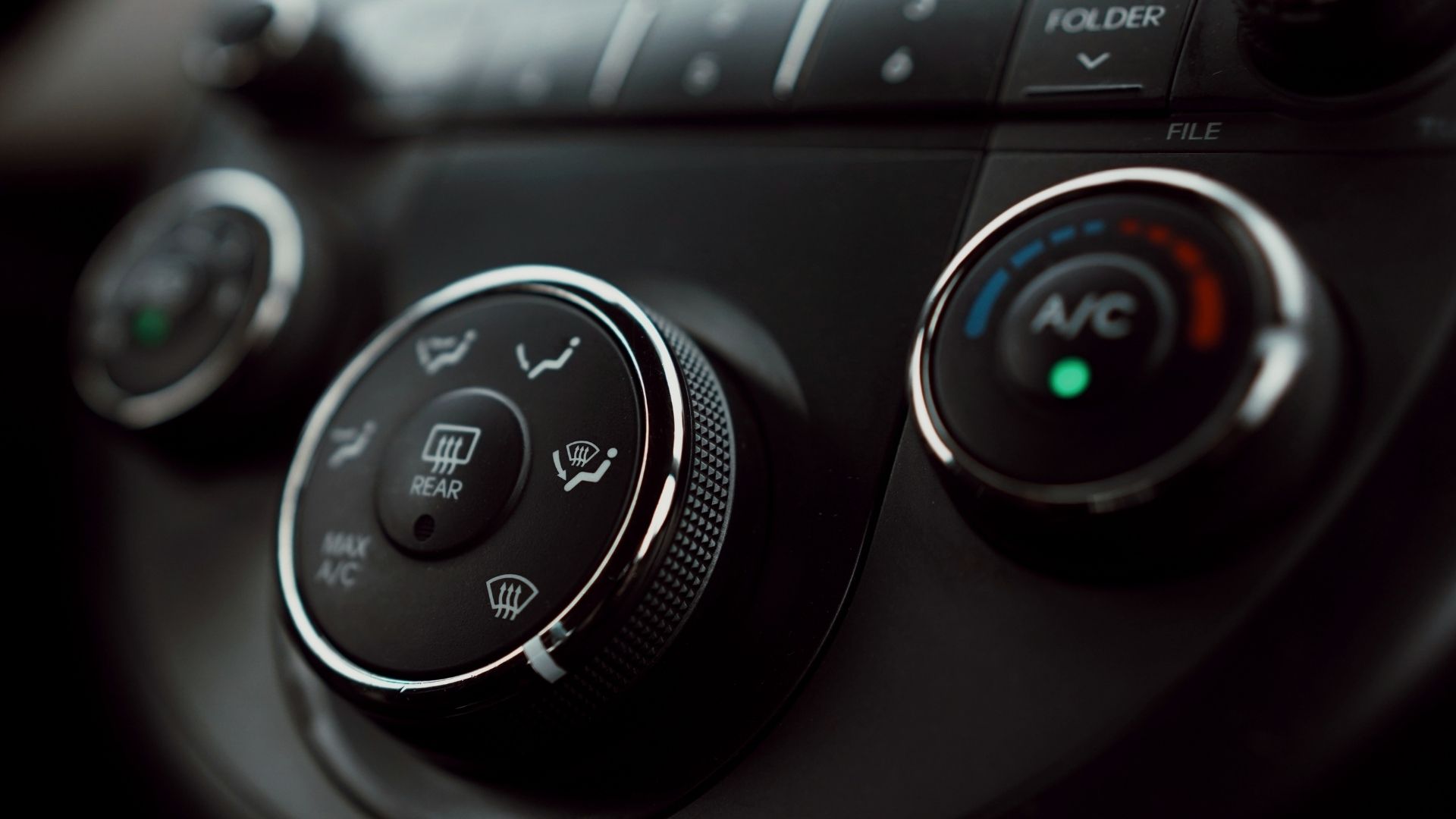 Close-up of a car climate control dial and illuminated AC button for car AC repair services.