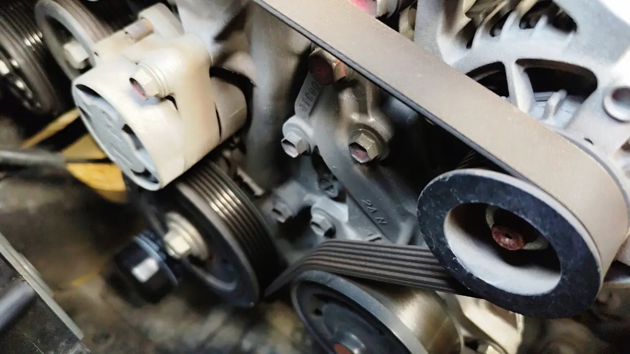 Engine belts and pulleys being inspected during a starter motor repair.
