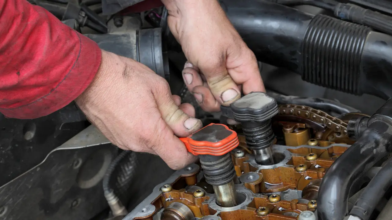 Mechanic hands removing ignition coils from an engine during a starter motor repair.