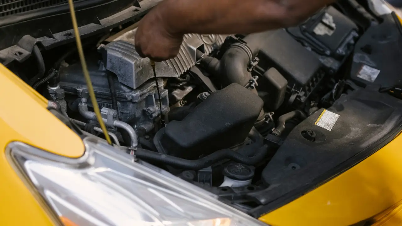 Technician checking engine components for a starter motor repair.